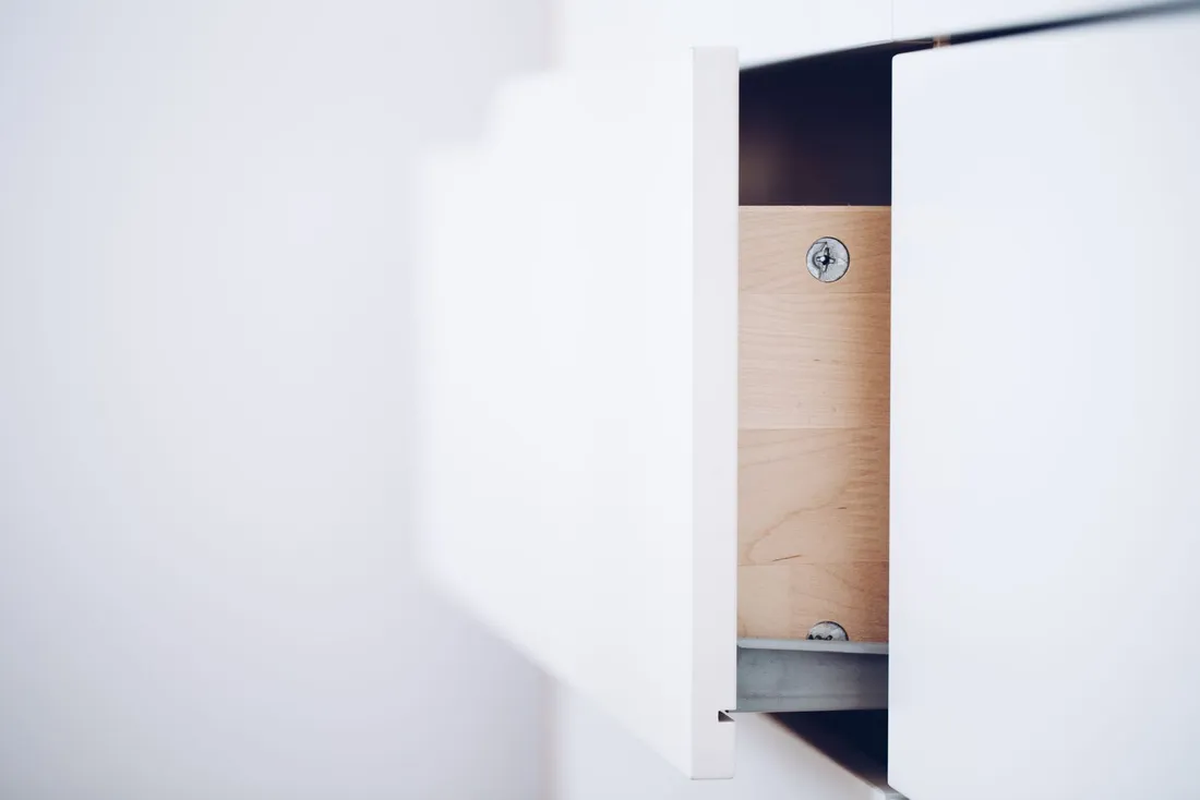 Lit 140 avec tiroirs latéraux ouverts sur parquet, linge plié rangé à l'intérieur
