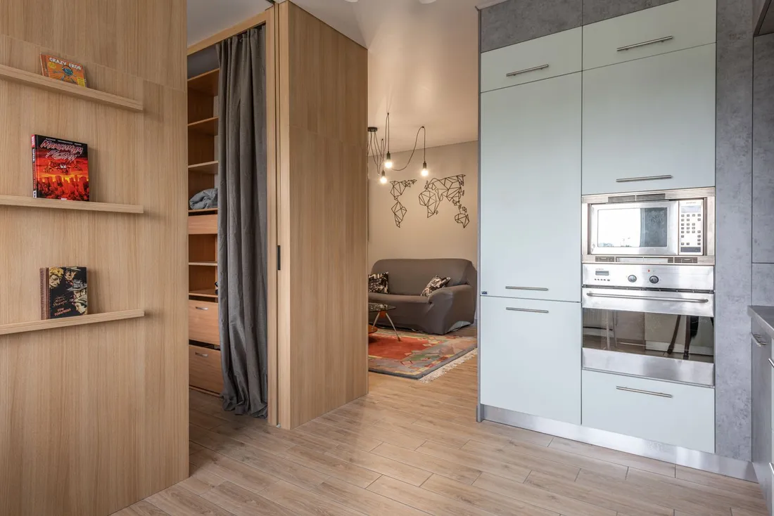 Petit salon de 15 m² encombré, canapé deux places et bibliothèque pleine